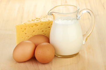 Big piece of cheese, glass jug with milk
