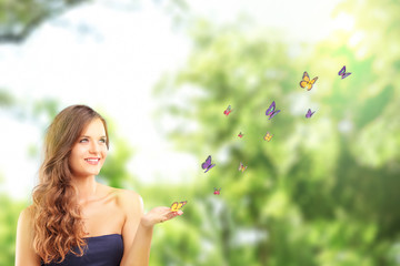 Beautiful female with a butterfly on her hand posing in a park - Powered by Adobe