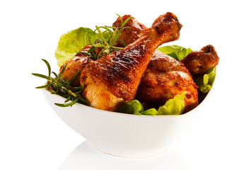 Grilled chicken legs and vegetables on white background