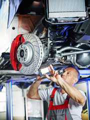 Car mechanic in a garage checks the brake
