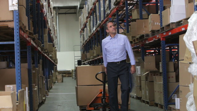 Businessman Pulling Pallet In Warehouse