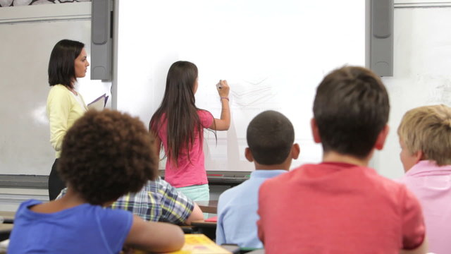 Pupil Standing At Front Of Class Writing On Board