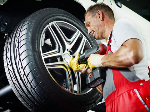 Motor mechanic is changing a tyre with new alu rim