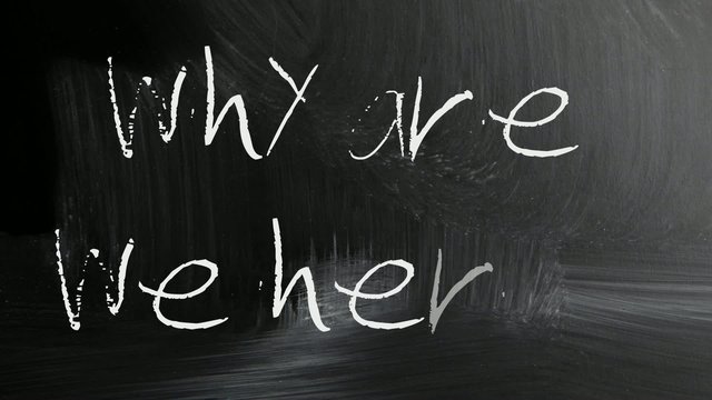 "why are we here" handwritten with white chalk on a blackboard