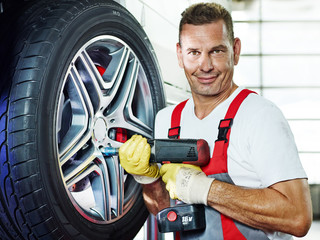 Car mechanic is changing a tyre in a garage
