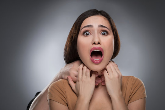 Choking. Portrait of shocked young woman with someones hands cho