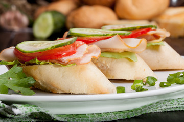 Three small sandwiches with ham and vegetables.