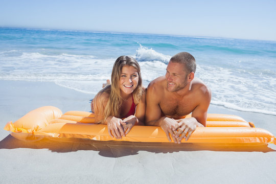 Cheerful cute couple in swimsuit lying on the beach