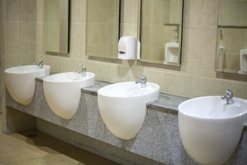 Wall mounted white ceramic toilet in brown tiled bathroom
