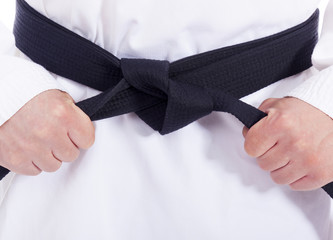 Closeup of a martial arts man tying his black belt © cristovao31