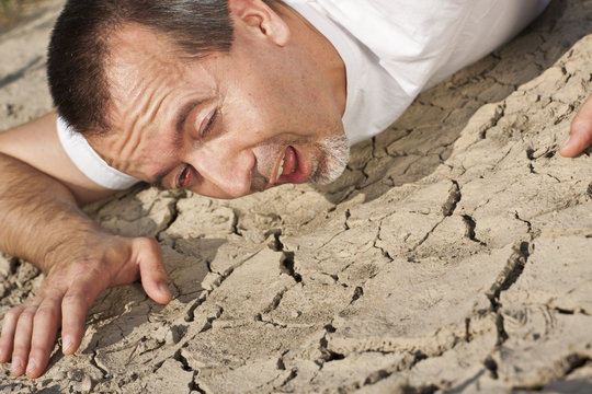 Mann auf vertrocknetem Boden sucht nach Wasser