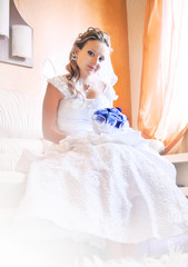 Bride is sitting on sofa waiting for groom