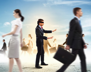 Businessman in blindfold among group of people