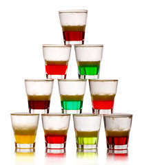 Pyramid of short colored alcohol cocktails isolated on white