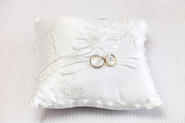 Obrączki ślubne na białej ozdobnej poduszce.