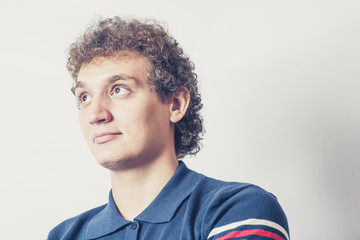 Obraz premium Curly haired young man on gray background with pensive
