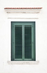 Fototapeta na wymiar Zamknięte okno z zielonym okiennice na białej ścianie