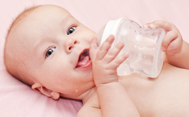 happy baby holding bottle and drinking water