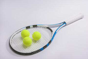 Closeup of a full length tennis racket and three balls