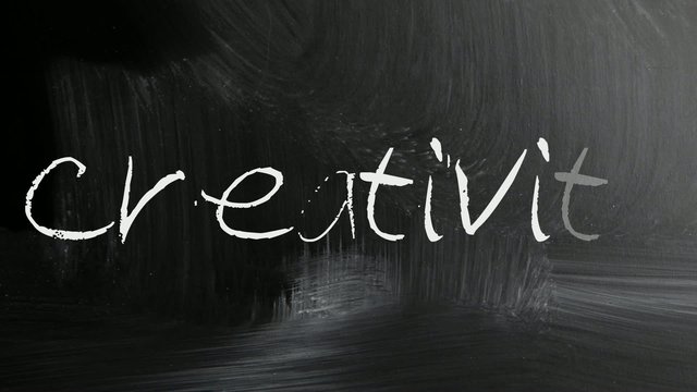 The word Creativity handwritten with white chalk on a blackboard