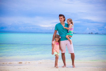 Young father and his two little kids walking by the sea