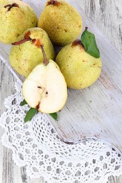 Pears on board on napkin on wooden background