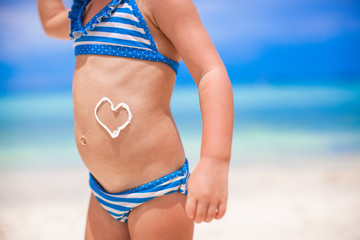 Close-up heart painted by sun cream on little girl stomach