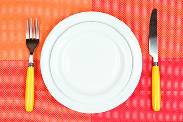 Knife, color plate and fork, on color background