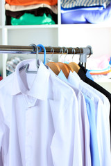 Variety of casual shirts on wooden hangers on shelves