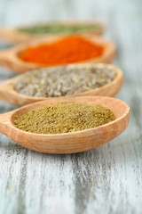 Assortment of spices in wooden spoons on wooden background