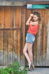 девушка стоящая около деревянной стены
