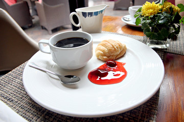 Coffee, bread and jam on a white plate.