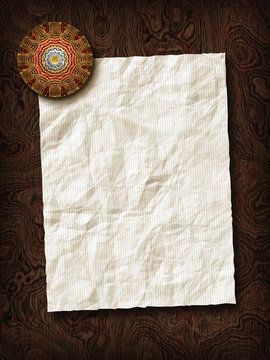 Paper sheet with paperweight on wooden background texture.