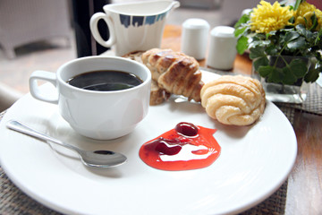 Coffee, bread and jam in white dish.