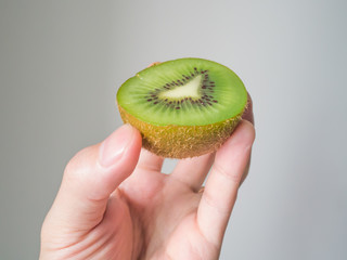 Hand holding half kiwi fruit