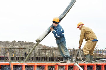 builder worker pouring concrete into form