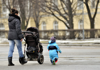 Mother with stroller walking near little son