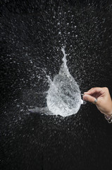 hand breaking a balloon with a needle