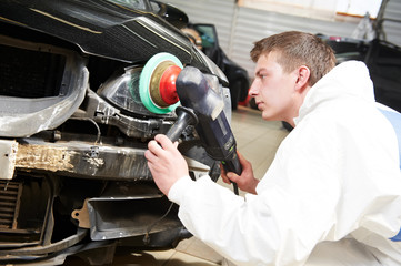 mechanic repairing and polishing car headlight