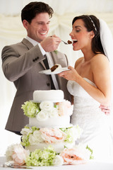 Groom Feeding Bride With Wedding Cake At Reception