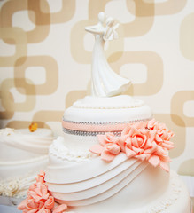 Obraz na płótnie Canvas sweet wedding cake with red flowers and porcelain couple