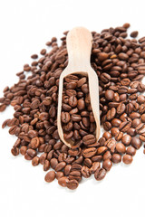 Coffee beans on wooden scoop.