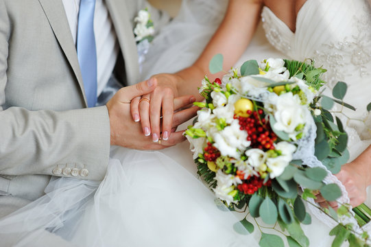 Groom and bride holding hands with wedding rings