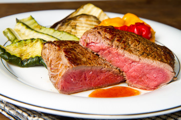 Delicious beef steaks on white dish with grilled vegetables