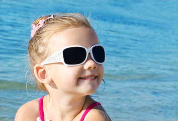 Fototapeta na wymiar Adorable smiling little girl on beach vacation