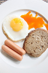 Eggs, toast and sausage in white dish.