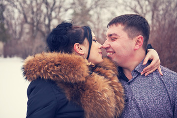 young couple kissing in the winter forest
