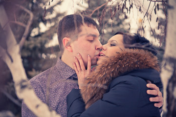 young couple kissing in the winter forest