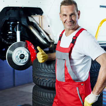 Car mechanic shows thumb up for changing a tyre