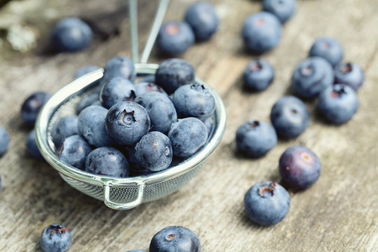 blueberries in a small colander on wooden background